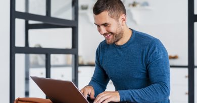 Homem usando notebook e sorrindo para a tela