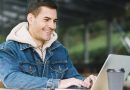 Homem sorrindo enquanto usa um laptop