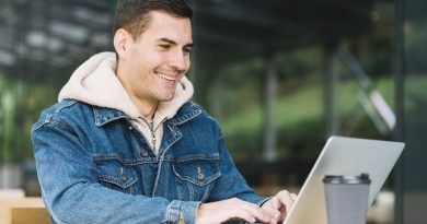 Homem sorrindo enquanto usa um laptop