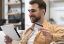 Homem segurando tablet com uma mão e cartão de crédito com a outra