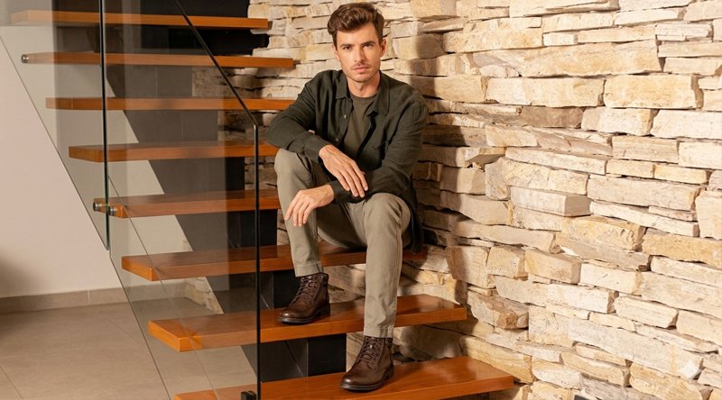 Bota casual masculina: modelos, combinações e dicas 1 Homem estiloso sentado em uma escada. Ele usa um modelo de bota casual masculina nos pés