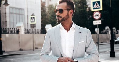 Homem usando camisa branca e blazer cinza, além de óculos de sol e relógio de pulso
