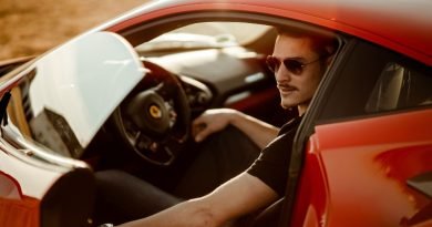 Homem de óculos escuros dentro de carro vermelho esportivo